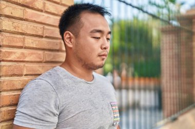 Young chinese man looking to the side with serious expression at street