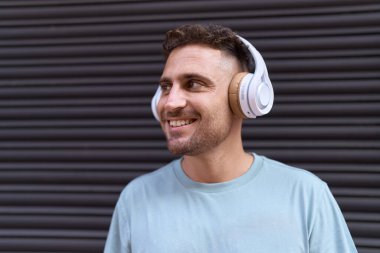 İzole edilmiş Black Metal arka planının başında dikilmiş müzik dinleyen genç İspanyol.