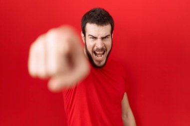 Gündelik kırmızı tişört giyen genç İspanyol adam kameraya kızgın ve sinirli bir şekilde seni işaret ediyor. 
