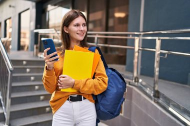 Üniversitede akıllı telefon kullanan genç sarışın kız öğrenci.