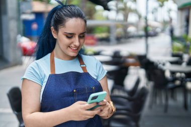 Young caucasian woman waitress smiling confident using smartphone at coffee shop terrace