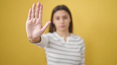 Genç, güzel, İspanyol bir kadın, sarı arka planda el kol hareketi yapıyor.