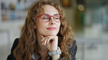 Genç bir iş kadını masada oturuyor ve ofiste düşünüyor.