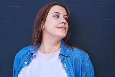 Genç, güzel, iri yarı, kendine güvenen bir kadın izole edilmiş siyah arka plana bakıyor.