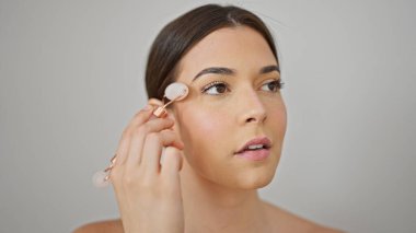 Genç ve güzel İspanyol bir kadın. Yüzüne masaj yapıyor. İzole edilmiş beyaz arka planda deri spor salonu kullanıyor.