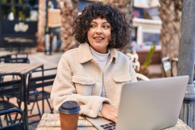 Kahve dükkanının terasında dizüstü bilgisayar kullanan genç ve güzel bir İspanyol kadın.