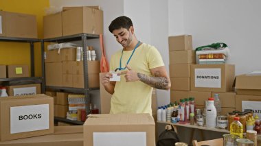 Genç İspanyol gönüllü gönüllü gülümsüyor. Yardım merkezindeki kimlik kartına işaret ediyor.