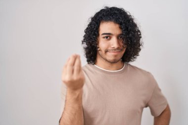 Beyaz arka planda duran kıvırcık saçlı İspanyol adam elleriyle ve parmaklarıyla italyan hareketi yapıyor. 