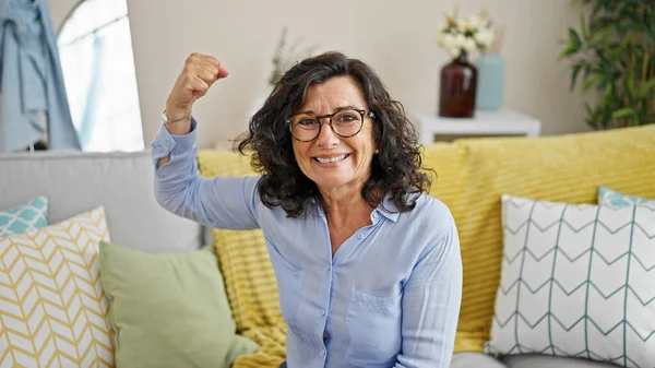 中年惊慌失措的女人充满自信地微笑着 在家里用胳膊做着强有力的手势 — 图库照片