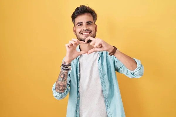 Sarı Arka Planda Dikilen Dövmeli Genç Spanyol Bir Adam Sevgiyle — Stok fotoğraf