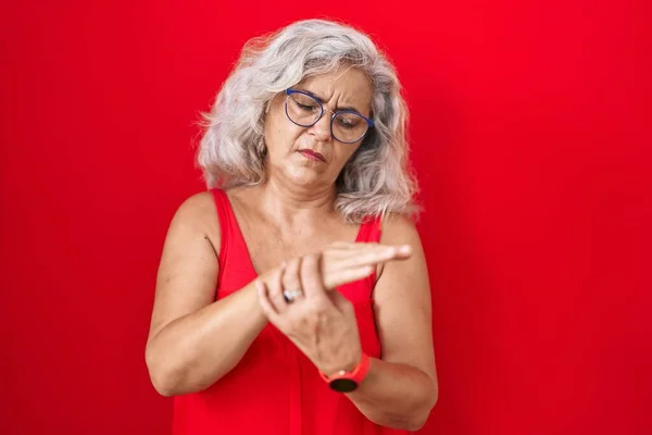中年妇女 白发苍苍地站在红底 手指头疼痛 关节炎 — 图库照片