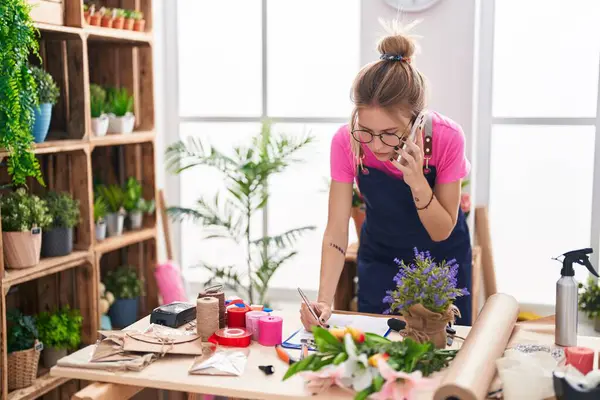 Genç sarışın kadın çiçekçi çiçekçide akıllı telefondan konuşuyor. Çiçekçide yazılı belge var.