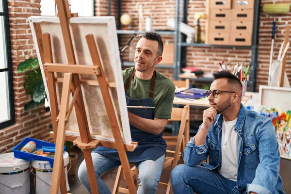 Two men artists drawing with relaxed expression at art studio