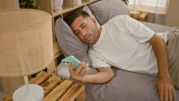 Atraente Jovem Hispânico Confortavelmente Deitado Cama Pijama Absorvido Usar Smartphone — Fotografia de Stock