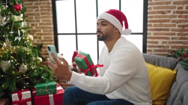 Noel Baba şapkalı adam akıllı telefon kullanıyor ve hediye fotoğrafı çekiyor.