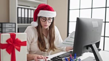 Noel Baba kıyafetli genç bir kadın iş yerinde Noel 'de çalışıyor. Noel Baba şapkalı kadın iletişim kurmak için bir video görüşmesi yapıyor.