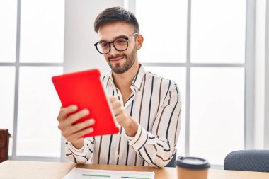 Young hispanic man business worker using touchpad at office