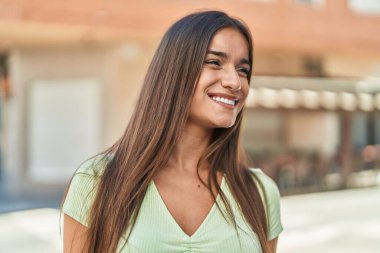 Young beautiful hispanic woman smiling confident looking to the side at street