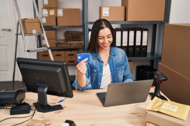 Young beautiful hispanic woman ecommerce business worker using laptop and credit card at office