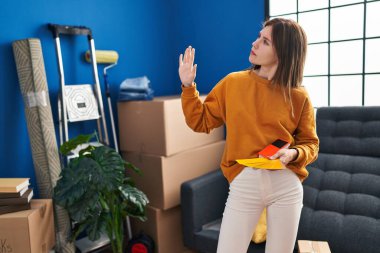 Elinde renk testi tutan genç sarışın kadın yeni evini düşünüyor.