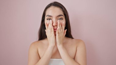 İzole edilmiş pembe arka planda masaj yapan güzel İspanyol bir kadın.