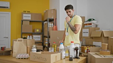 Genç İspanyol gönüllü yardım merkezinde bağış kutusuna ürünler koyuyor.