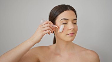 Genç ve güzel İspanyol bir kadın. Yüzüne masaj yapıyor. İzole edilmiş beyaz arka planda deri spor salonu kullanıyor.