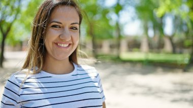 Ortadoğulu kadın parkta kendinden emin gülümsüyor.