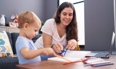 Anne ve oğlu evdeki kanepede oturmuş defter çiziyorlar.
