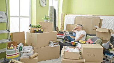 Yeni evindeki kanepede kendinden emin gülümseyen beyaz bir genç.