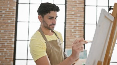 Sanat stüdyosunda resim çizen genç bir İspanyol.