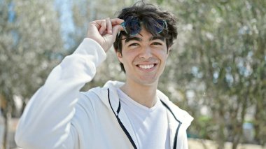 Young hispanic man smiling confident wearing sunglasses at park