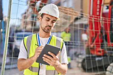 Young hispanic man architect drawing on touchpad at street