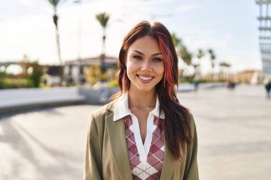 Sokakta kendine güvenen beyaz kadın gülümsüyor.