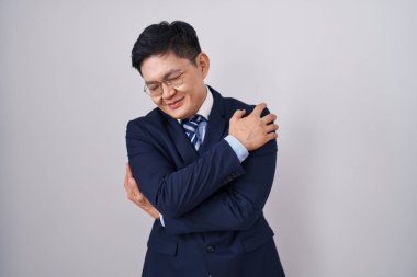 Genç Asyalı takım elbiseli ve kravatlı mutlu ve pozitif, kendinden emin gülümseyen bir adam. Sevgi ve özgüven. 