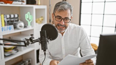 Çekici gri saçlı genç İspanyol adam radyo dalgalarını sallıyor! İçerideki radyo stüdyosu, haber muhabiri olarak büyüleyici hikayeler ve olaylar sunuyor..