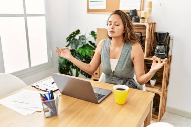 Young beautiful hispanic woman business worker doing yoga exercise at office
