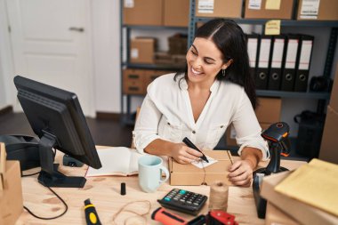 Genç, güzel, İspanyol bir kadın. İş adamı. Ofiste bir pakete yazıyor.