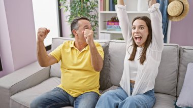 İspanyol baba ve kızı sevinçle futbol maçının zaferini kutluyorlar, oturma odasında birlikte televizyon izliyorlar rahat bir kanepede dinlenirken.