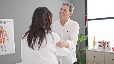 Kıdemli erkek ve kadın doktor ve hasta klinikte tıbbi danışmanlık yapıyorlar.