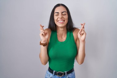 İzole edilmiş arka planda duran genç bir kadın umut ve gözlerin kapalı bir şekilde gülümseyerek bana işaret ediyor. Şans ve batıl inançlar. 