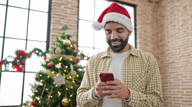 Genç İspanyol adam Noel 'i evde akıllı telefon kullanarak kutluyor.