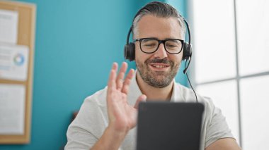 Gri saçlı iş adamı ofiste video görüşmesi yapıyor.