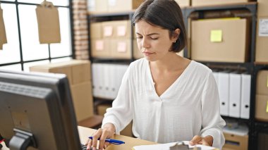 Genç, güzel İspanyol bir kadın. İş adamı. Ofisteki belgelerde bilgisayar kullanıyor.