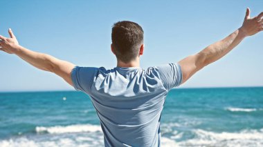 Genç İspanyol turist kollarını açmış deniz kenarında bekliyor.