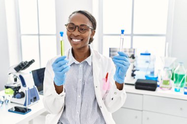 Laboratuvarda test tüpleri tutan Afrikalı Amerikalı kadın bilim adamı.