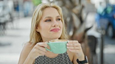 Kahve dükkanının terasında kahve kokan genç sarışın kadın.