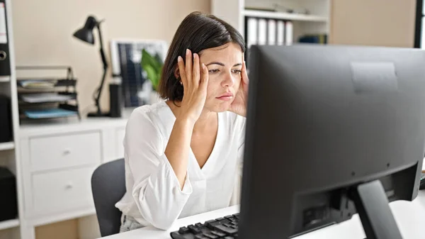 Young beautiful hispanic woman business worker stressed using computer at office