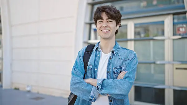 Young hispanic man student smiling confident standing with arms crossed gesture at university