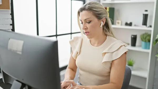 若い金髪女性ビジネスワーカー オフィスで働くコンピュータとイヤホンを使用して — ストック写真